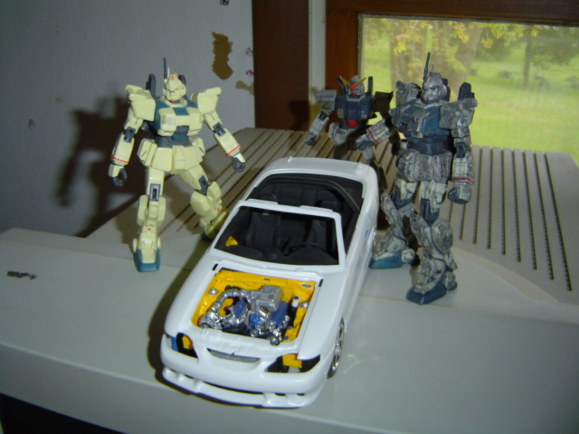 White model convertible with open hood and engine detail, flanked by three robot figures