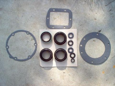 1988 Ford Bronco - A collection of seals and gaskets for a vehicle transfer case rebuild is displayed on a concrete surface.