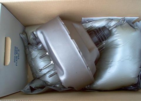 1988 Ford Bronco - A brake booster is shown packed in a cardboard box with protective material. Text on the box indicates part number and specifications.
