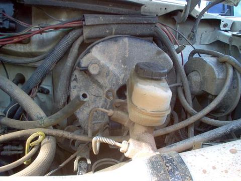 1988 Ford Bronco - Close-up view of the brake booster and master cylinder in an engine bay.