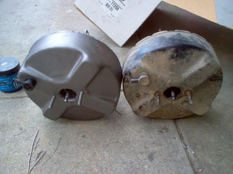 1988 Ford Bronco - A new brake booster sits next to a used one, both resting on a concrete surface.