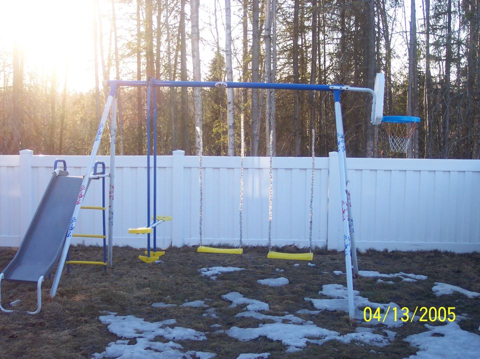 Swing set with slide and basketball hoop in a backyard
