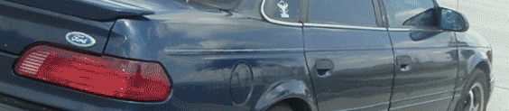 Dark blue 1993 Ford Taurus sedan, rear quarter view, with a spoiler and a Ford badge