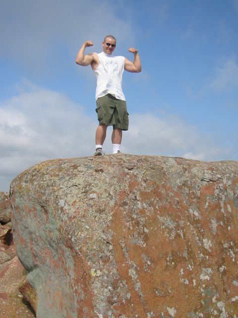 1986 Ford Bronco - A man poses by flexing his biceps while standing on a large rock formation.