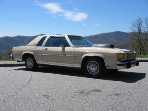 1985 Ford LTD Crown Victoria - Tan 1985 Ford Crown Victoria LTD coupe with a hood scoop parked on a mountain overlook.