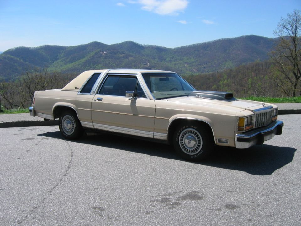 Beige two-door Ford LTD Crown Victoria parked at a mountain overlook, three-quarter view