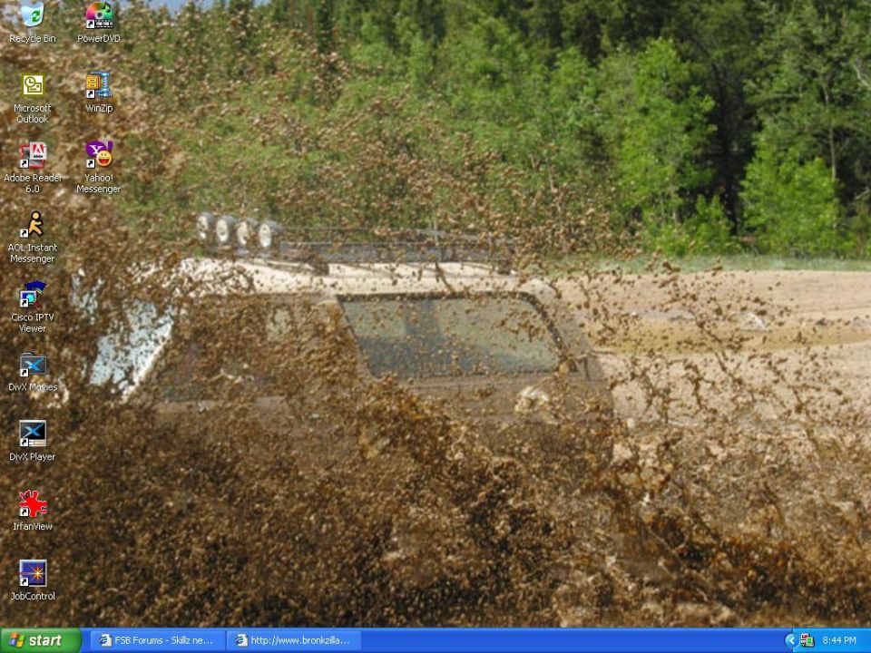 1988 Ford Bronco covered in mud, driving through a muddy area with trees in the background