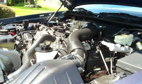 1998 Ford Crown Victoria - The engine compartment of a vehicle is shown with the hood open, revealing the engine and its associated parts.