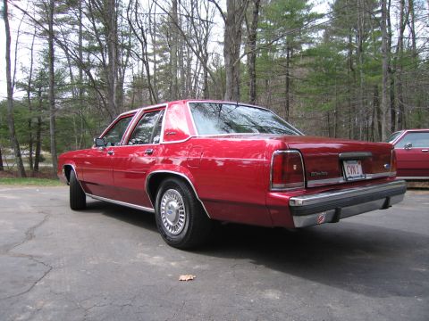 1991 Ford LTD Crown Victoria - This red 1991 Ford Crown Victoria LTD is parked on a driveway with trees in the background.
