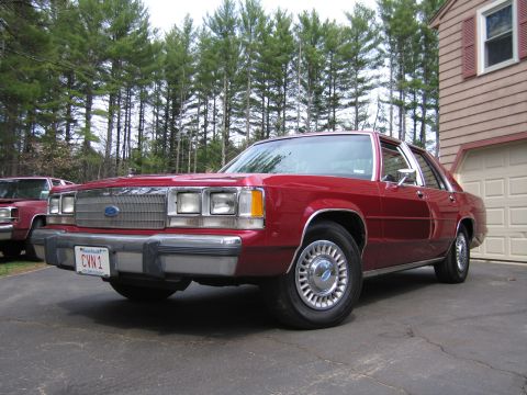 1991 Ford LTD Crown Victoria - A red 1991 Ford Crown Victoria LTD sedan is parked in a driveway next to a garage.