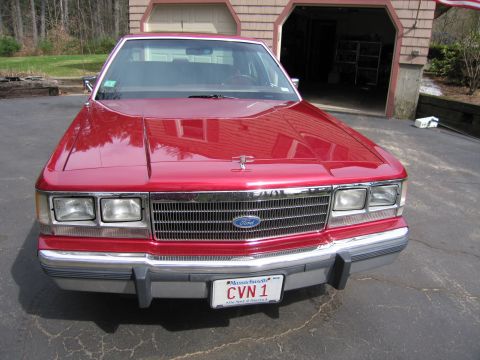 1991 Ford LTD Crown Victoria - This Ford sedan, likely from the 1980s, is parked in front of a garage.