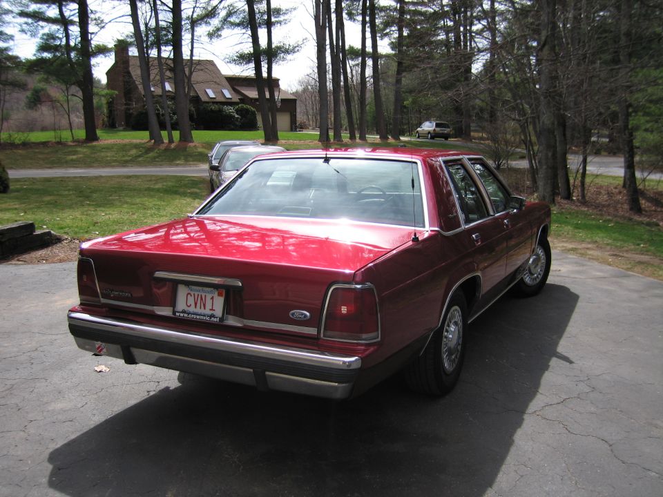 Red sedan parked in a driveway, showing the rear and side. License plate reads CVN 1