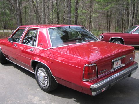 1991 Ford LTD Crown Victoria - Rear view of a red 1991 Ford Crown Victoria LTD, parked next to another vehicle.
