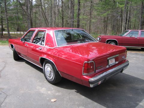 1991 Ford LTD Crown Victoria - A red sedan is parked on a driveway with another red sedan behind it.