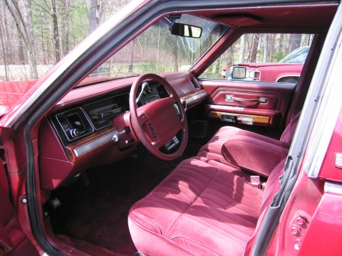 1991 Ford LTD Crown Victoria - The interior of a 1991 Ford Crown Victoria LTD features red velour seats and wood grain trim. Another red vehicle is visible in the backgro…