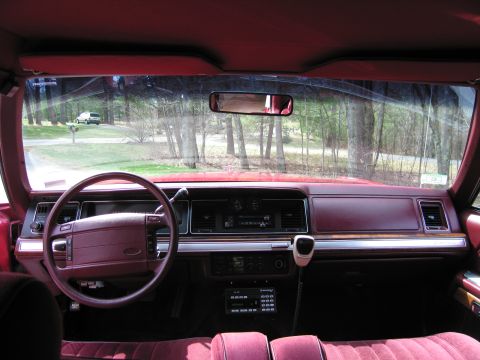 1991 Ford LTD Crown Victoria - The interior of a maroon car is shown, with a white SUV visible in the distance outside.