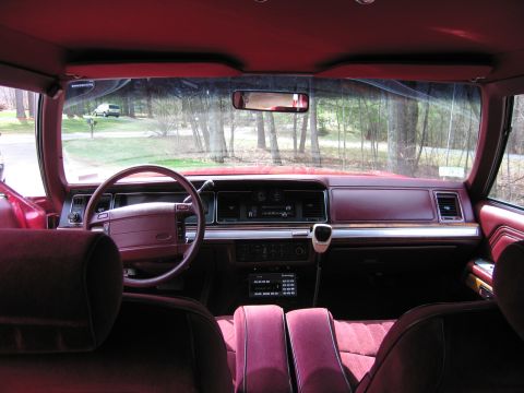 1991 Ford LTD Crown Victoria - Interior view of a maroon car, showing the dashboard and seats, with another vehicle visible outside.