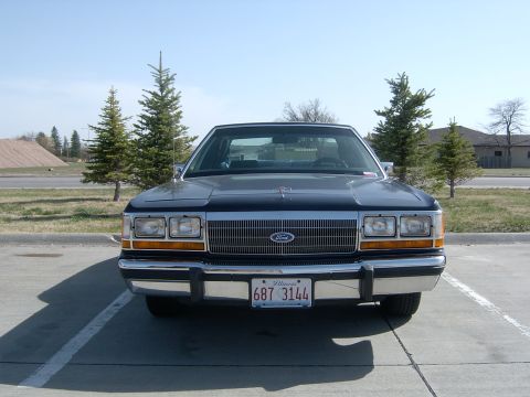 1990 Ford Crown Victoria - The front grille and headlights of a 1990 Ford Crown Victoria are visible.