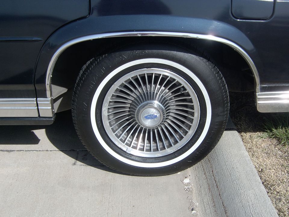1990 Ford Crown Victoria wheel with chrome hubcap and whitewall tire