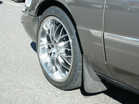 2001 Mercury Grand Marquis - Close-up view of the front wheel and fender area of a dark gray sedan, custom chrome rims.
