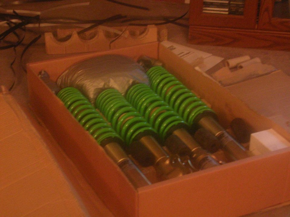 Box of four green coilover suspension assemblies