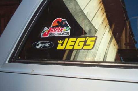 1988 Ford Bronco - Stickers adorn the rear quarter window of a white vehicle.