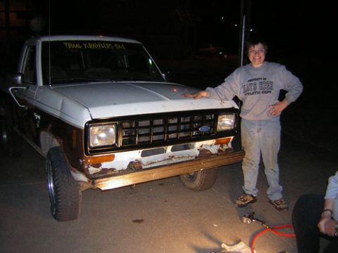1986 Ford Bronco II - A person stands next to a white and brown Ford Ranger pickup truck at night.