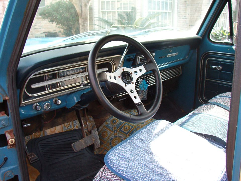 Blue 1967 Ford F-100 interior with aftermarket steering wheel and patterned seat covers