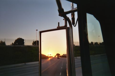 1990 Ford Bronco - golden sunset over a road reflected in a large vehicle side mirror, with grassy median and trees alongside.