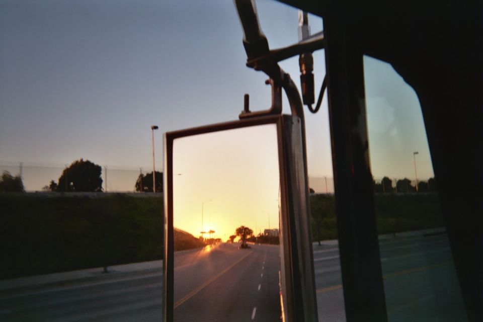 Sunset reflected in a truck's side mirror over a roadway and median