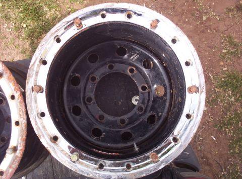 1988 Ford Bronco - Two large chrome wheels with visible rust on the lug nuts sit on the ground.