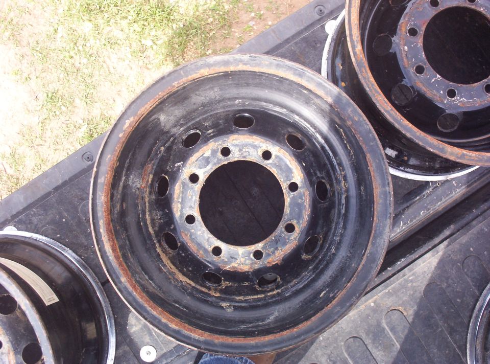 Bare black steel wheels with 10-lug bolt pattern lying in a pickup bedliner