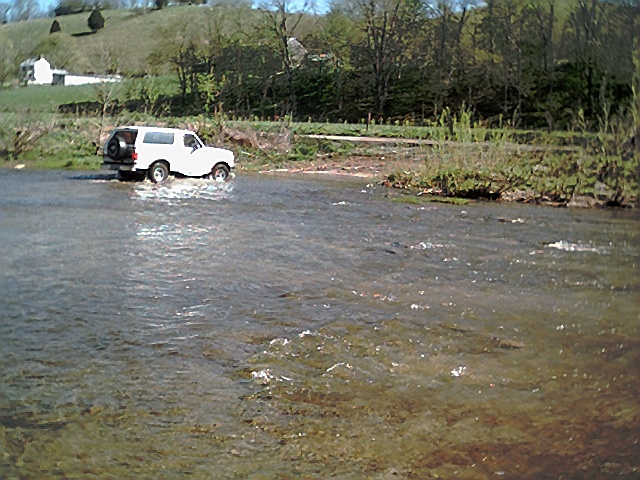 1995 Ford Bronco crossing a shallow river, side view