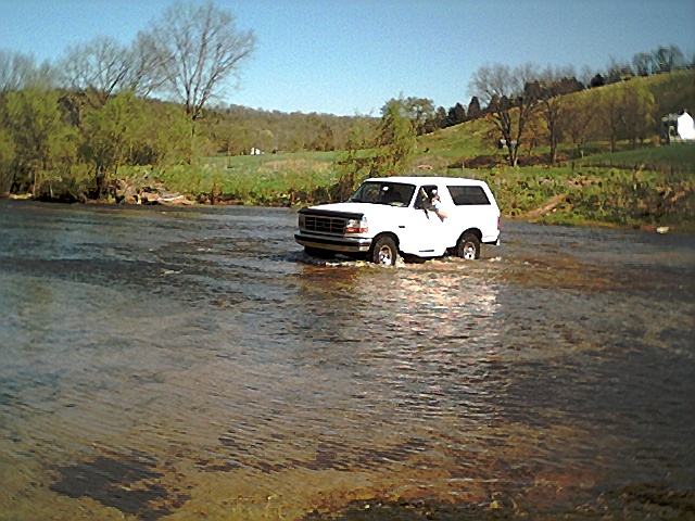 White 1995 Ford Bronco crossing a creek