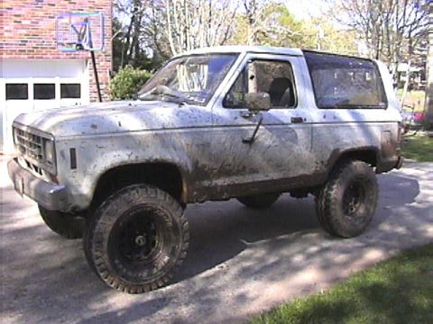 1984 Ford Bronco II - Muddy 1984 Ford Bronco II sits in a driveway with a basketball hoop in the background.