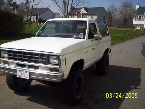 1984 Ford Bronco II - This 1984 Ford Bronco II is shown in a three-quarter front view, parked on a paved surface with houses in the background.