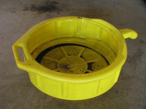 2000 Ford Excursion - A yellow oil drain pan holds dark fluid, with a label visible on the rim.