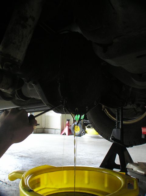 2000 Ford Excursion - Old fluid is being drained from the rear differential of a vehicle.
