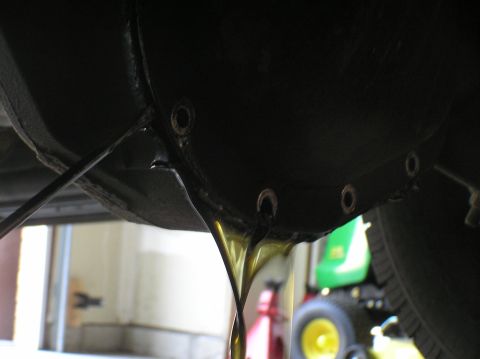 2000 Ford Excursion - Differential fluid is draining from a vehicle, with a green tractor visible in the background.