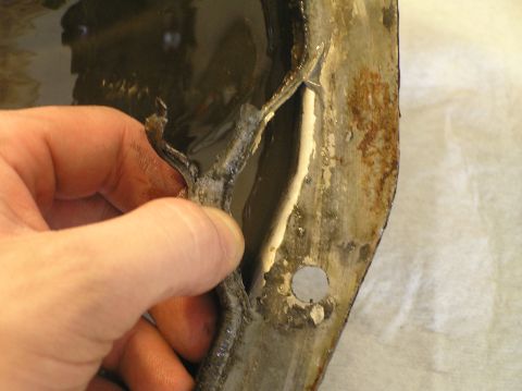 2000 Ford Excursion - Damaged differential cover removed for fluid replacement, showing rust and a torn seal.