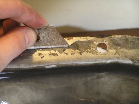 2000 Ford Excursion - Scraping old gasket material from a metal surface with a utility knife blade.