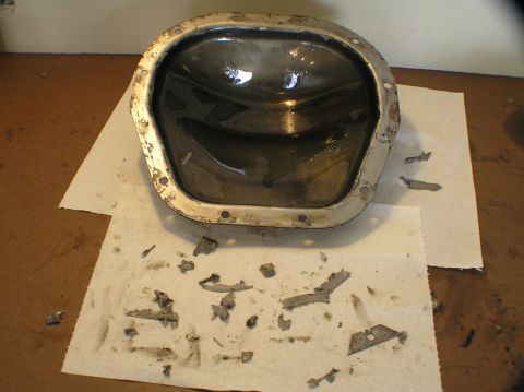 2000 Ford Excursion - A differential fluid pan, removed from a vehicle, contains dark fluid and metal debris.