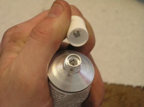 2000 Ford Excursion - A hand holds an open tube of ointment, with the white cap removed.