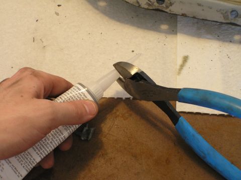 2000 Ford Excursion - Cutting the tip off a tube of sealant with blue-handled pliers.