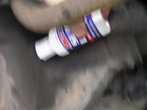 2000 Ford Excursion - A bottle of fluid is being poured into the undercarriage of a vehicle.