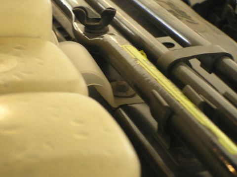 2000 Ford Excursion - A close-up view of various engine components, a metal bar with a yellow stripe and a wing nut fastener.