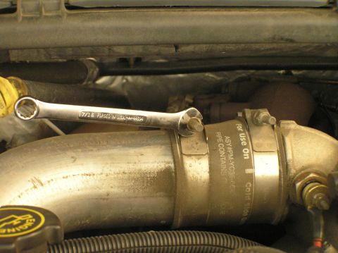 2000 Ford Excursion - A wrench is positioned on a metal pipe in an engine bay, with visible text indicating its purpose and location.
