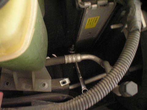 2000 Ford Excursion - Engine bay detail with coolant reservoir and AC line, wrench visible on a bolt.