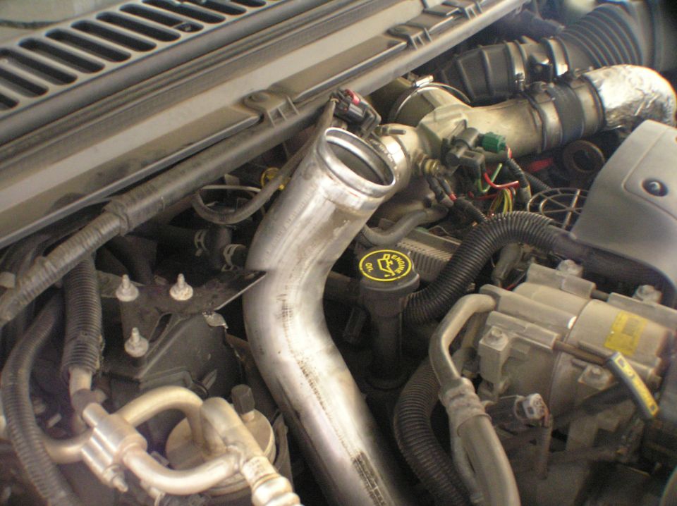 Engine bay close-up with aluminum intake tube, yellow oil cap and wiring