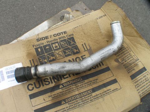 2000 Ford Excursion - Metal pipe with rubber fittings, likely a coolant or intake hose, lies on shipping cardboard.